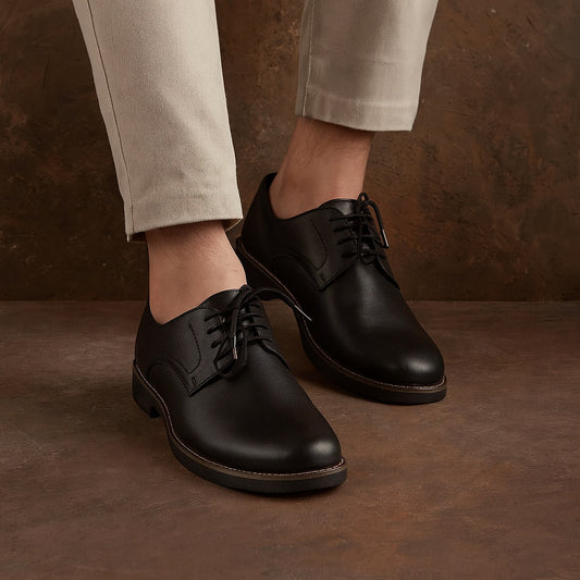 Black leather shoes worn with beige pants on a brown background